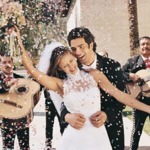 A bride and groom smiling while confetti falls down on them