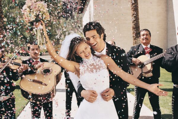 A bride and groom smiling while confetti falls down on them